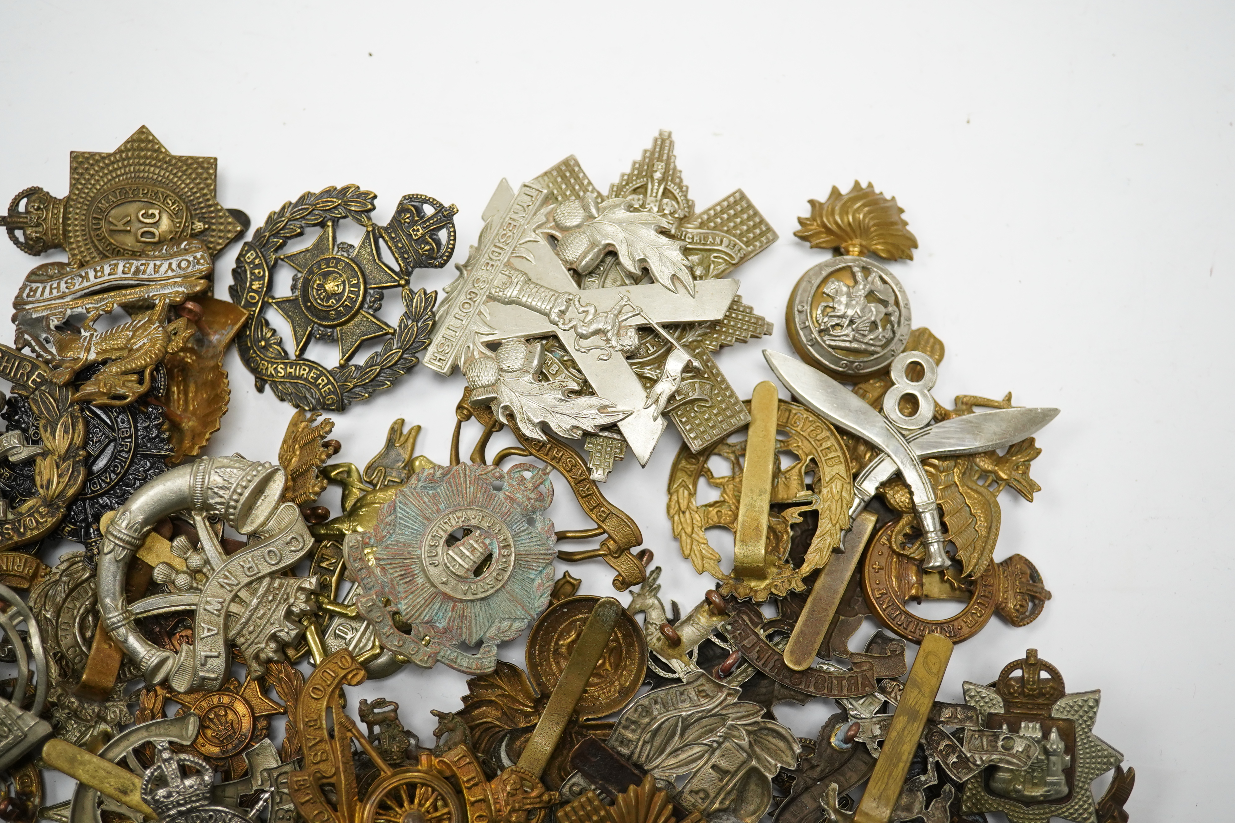 Sixty military cap badges, including; the Hampshire regiment, the South Lancashire Regiment, Prince of Wales Volunteers, the Tyneside Scottish Regiment, the Royal Artillery, the Norfolk Regiment, the Army Ordinance Corps